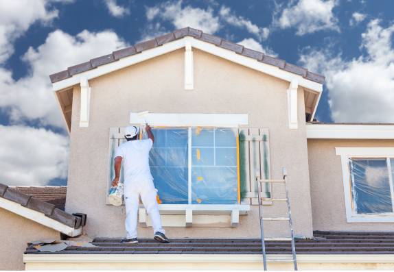 Painter wearing white painting exterior of house